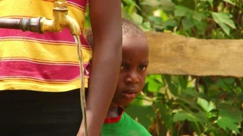 Cute little boy hide behind his sister who is fetching potable water Vidéo 201936543