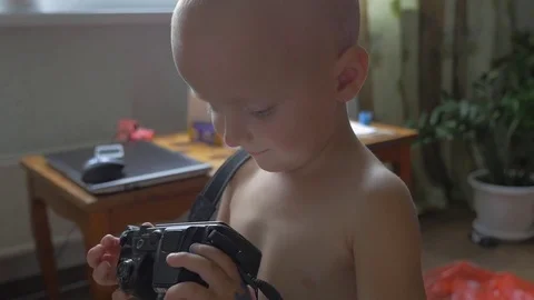 Cute little boy holding camera in his hand and looking at the pictures on the Video stock 80005491
