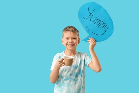 Cute little boy holding speech bubble with word YUMMY and cup of cocoa on blu Stock Photos