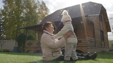 Cute little boy is hugging his grandmother on the lawn of country house Stock Footage 223160855