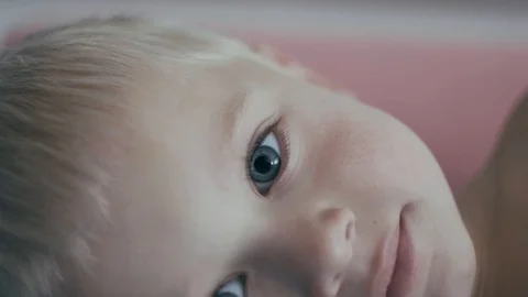 A cute little boy is looking into the camera and is happy on a slightly pink bac Stock Footage 98377036