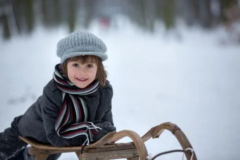 Cute little boy, lying down on sledge, smiling at camera Stock Photos