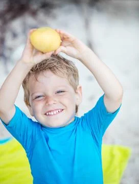 Cute little boy with mango fruit on beach Stock Photos