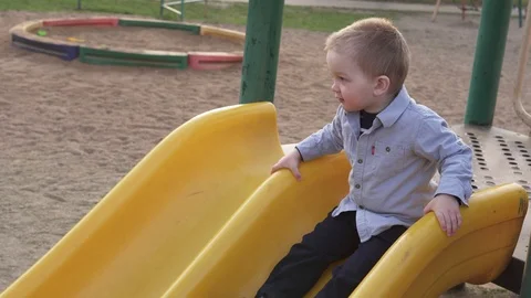 Cute little boy moving down from children's slide in park Stock Footage 88973002