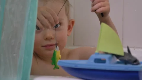 Cute little boy playing in the bathroom, catching fish Видео 130759526
