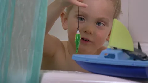 Cute little boy playing in the bathroom, catching fish Video stock 130760322