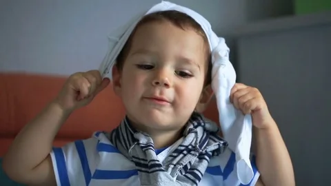 Cute little boy playing with clothes and smiling to the camera Stock Footage 84180306
