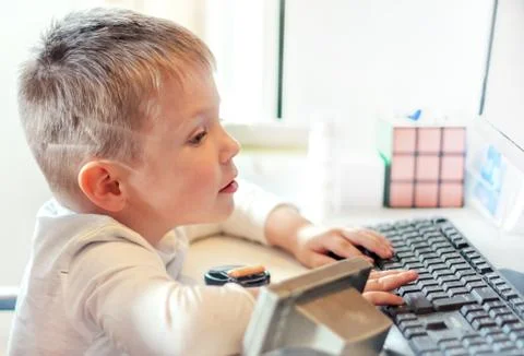 Cute little boy playing at the computer at home. Stock Photos