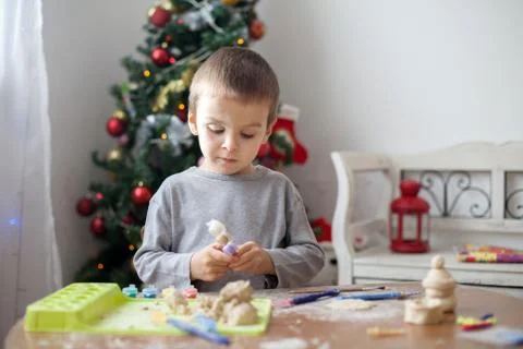 Cute little boy, playing with modeling dough, molding figures at home on Chri Stock Photos