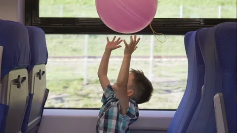 Cute little boy playing with pink balloon in the train, while it moving. Child Stock Footage 93588877