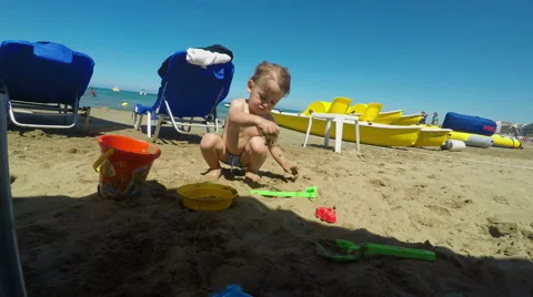 Cute Little Boy Playing with Sand on the Beach Stock Footage 61351981