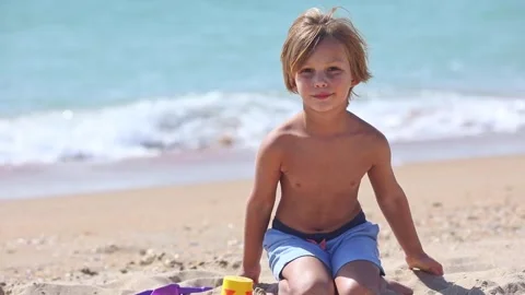 Cute little boy playing on the sandy summer beach near the sea. Summer time.  Stock Footage 261181970