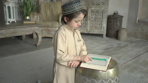 Cute little boy in prayer hat and arabic clothes with rosary beads reading holy Stock Footage 132003404