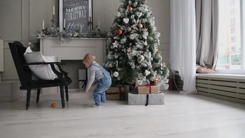 A cute little boy pulls a tangerine out from under a chair in a room in a Stock Footage 166040965