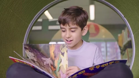 Cute little boy reading a book in the library Stock Footage 242608111