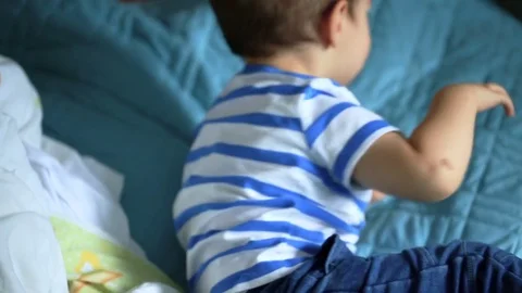 Cute little boy sitting on bed and playing with clothes Stock Footage 84179965