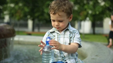 Cute, little boy sitting next to the fountain in the park Stock Footage