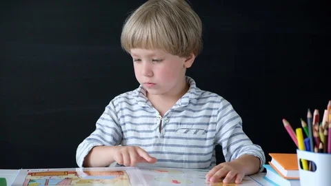 Cute little boy sitting at the table and reading. Child from elementary school Stock Footage 111759601