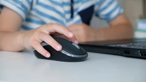 Cute little boy sitting at the table and playing or working on a computer. Child Stock Footage 111759822