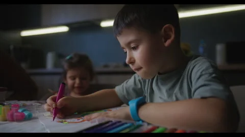 Cute little boy sitting at table drawing on paper and playing at home. Childhood Stock Footage 269886877