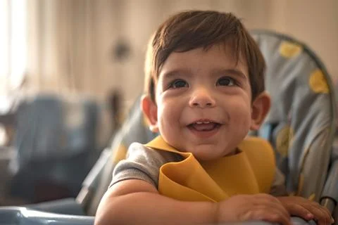 Cute little boy smiling while sitting in a high chair at home. Childhood concept Stock Photos