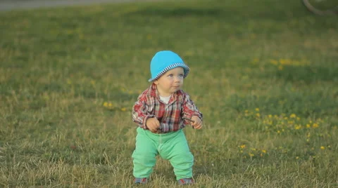 Cute little boy takes the first steps in the park on the grass Stock Footage 64997201
