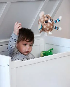 Cute little boy throwing toys out of the toy box 库存照片