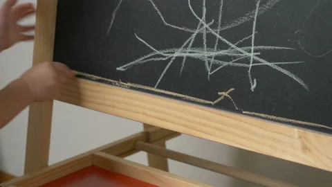 Cute little boy (toddler, two years old) is drawing on the chalkboard. Stock-Footage 100876072