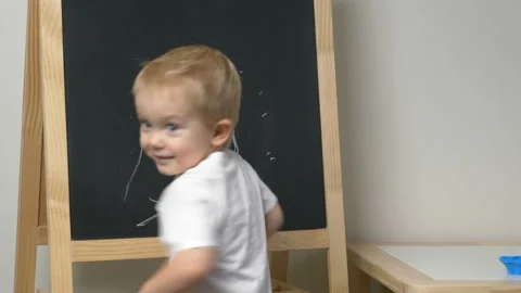Cute little boy (toddler, two years old) is drawing on the chalkboard. Video stock 100876374