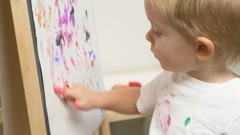 Cute little boy (toddler, two years old) is painting Видео 102378084