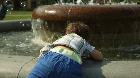 Cute, little boy trying to get into the fountain Stock Footage 76980029