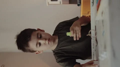Cute little boy using glue stick at desk in room. Home workplace. Family Stock Footage 256924614
