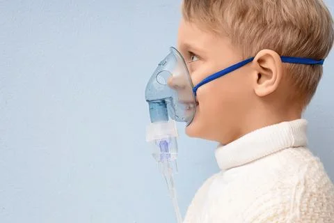 Cute little boy using nebulizer on light background, closeup Stock Photos