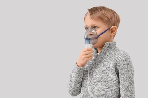 Cute little boy using nebulizer on light background Stock Photos