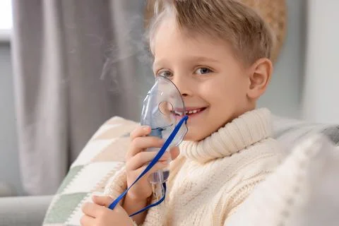 Cute little boy using nebulizer at home, closeup Stock Photos