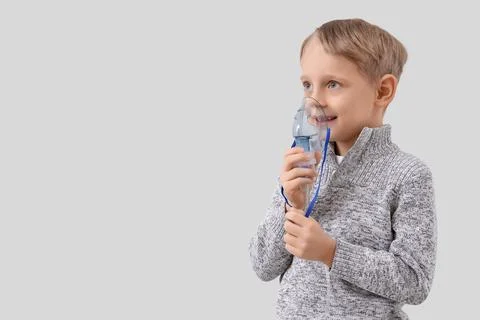 Cute little boy using nebulizer on light background Stock Photos