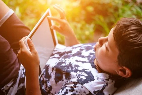 Cute little boy using tablet in sunlit park 스톡 사진