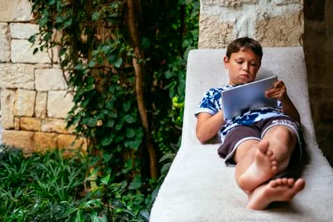 Cute little boy using tablet in sunlit park Stock Photos