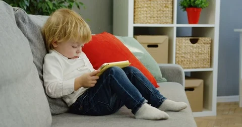 Cute little boy watching something on the tablet computer screen while sitting Stock Footage 82915945