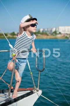 Cute little captain kid wearing captain hat and trendy sunglasses peering int Stock Photos