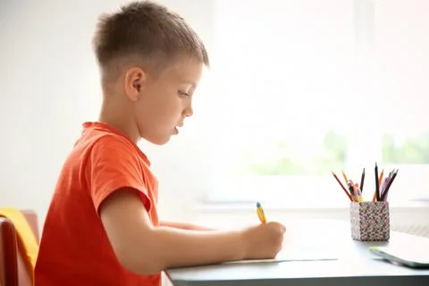 Cute little child doing assignment at desk in classroom. Elementary school Stock Photos