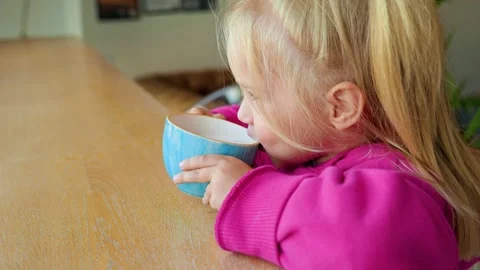 Cute little child sits at a table and drinks from a mug in front of panoram.. Stock Footage 319639649