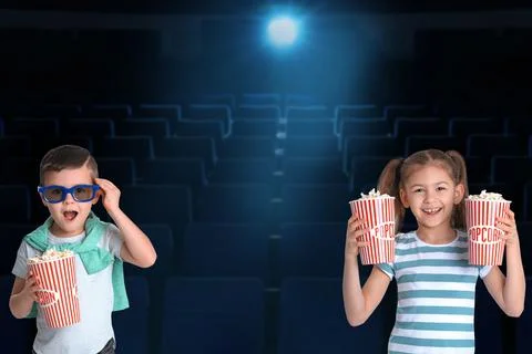 Cute little children with popcorn in cinema hall Stock Photos