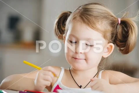 Cute little girl is drawing with colored pencil at home Stock Photos