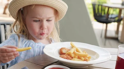 Cute little girl eats  in a cafe with a veranda outside Stock Footage 315066010