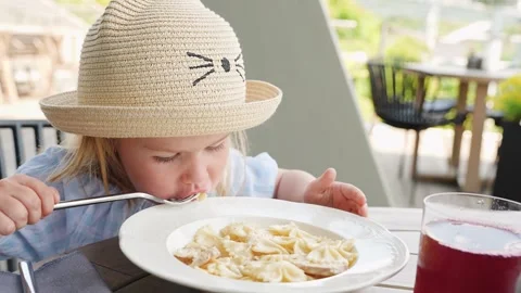 Cute little girl eats  in a cafe with a veranda outside Stock Footage 315066059