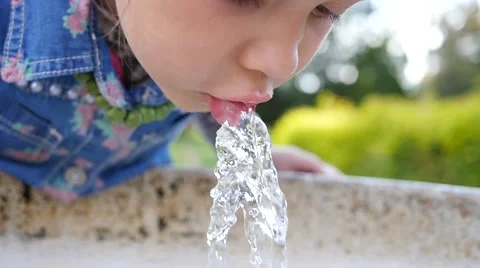 Cute little girl face portrait drink water in a park from drinking fountain slow Stock Footage