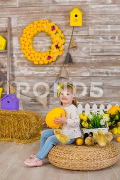 Cute little girl in jeans and white blouse playing hide and seek with a chick Stock Photos