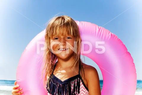 Cute little girl with pink swim ring on the beach Stock Photos