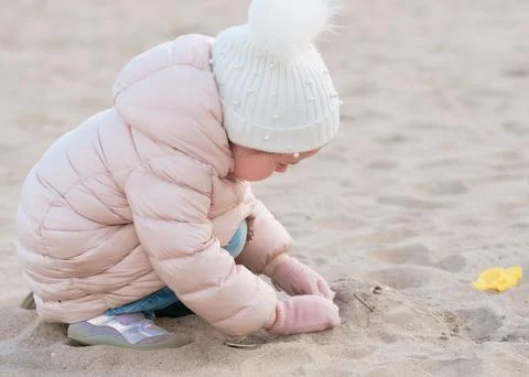 Cute little girl is playing on an empty beach on a cold day Stock Photos